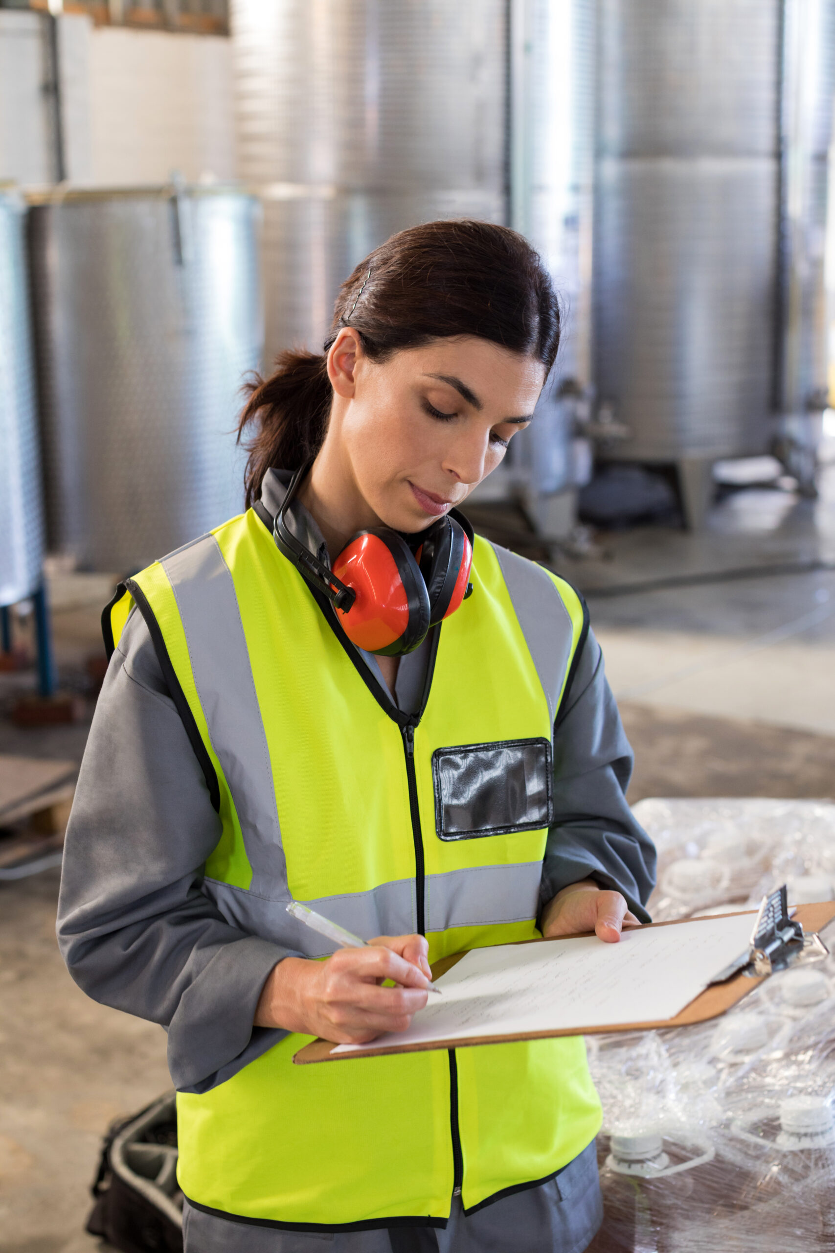 Female work safety manager writing in clipboard at a factory