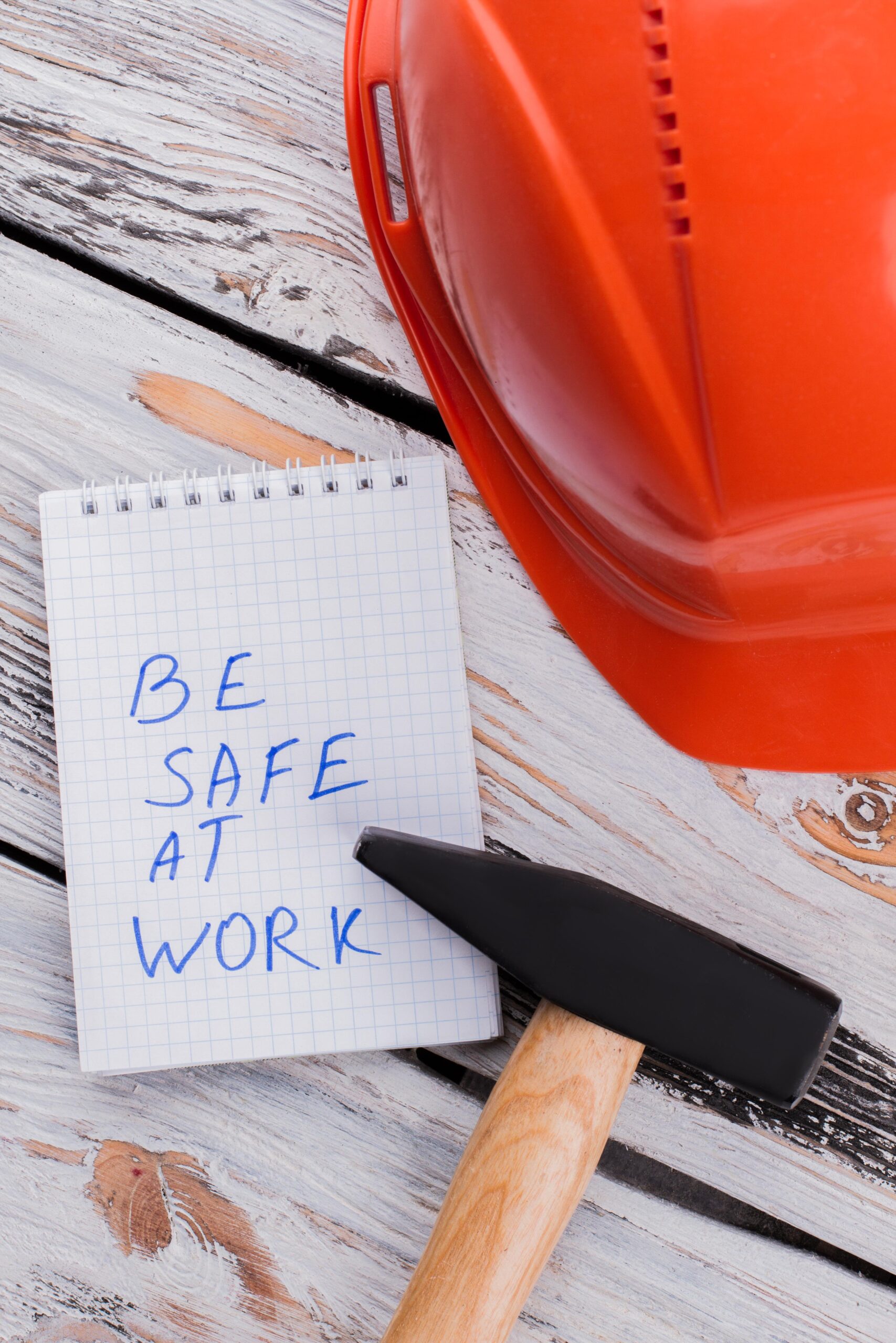 Be safe at work note with hammer and helmet on wood